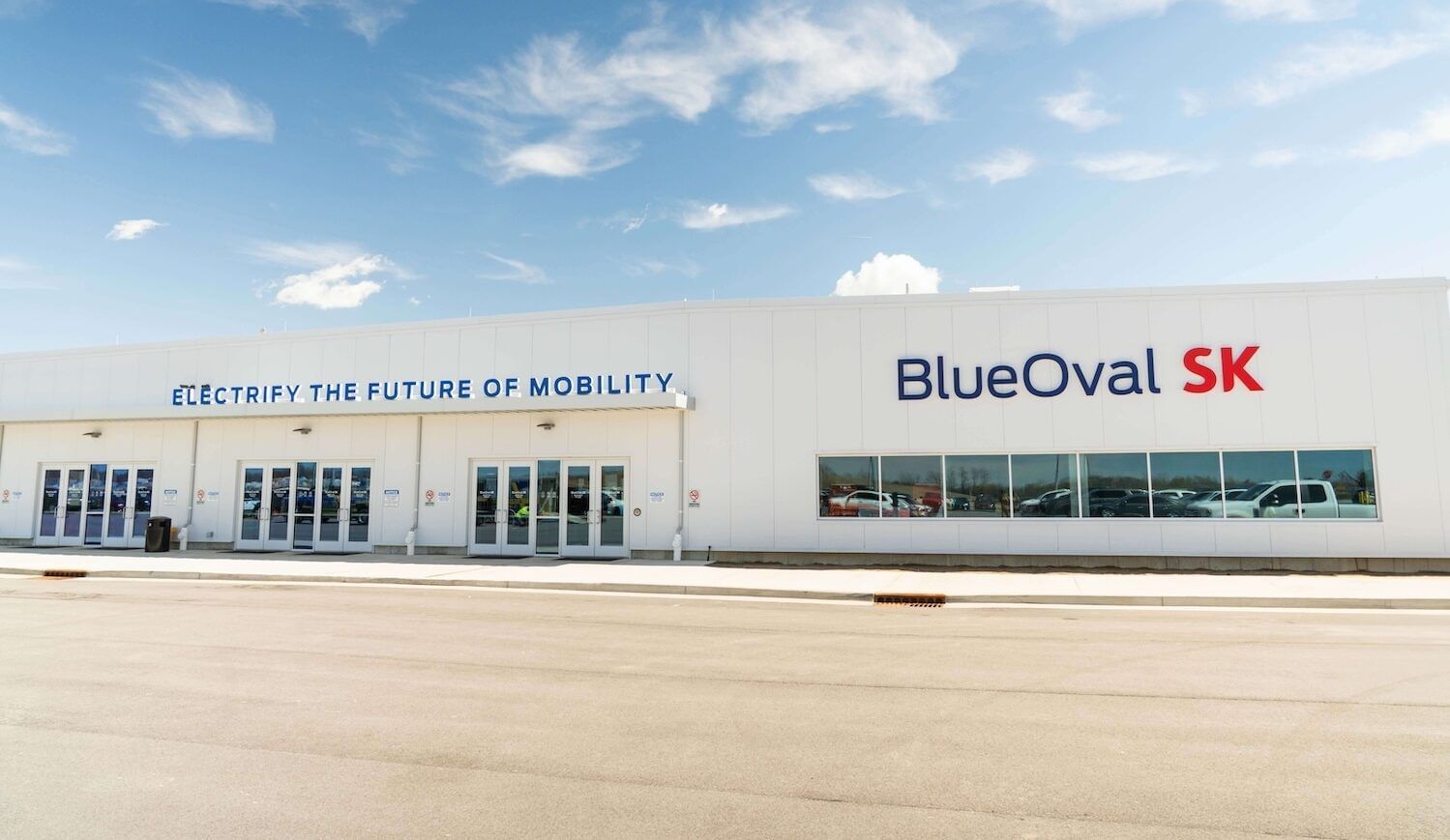 A low-rise factory with signs that read "Electrify the future of mobility" and "BlueOval SK"