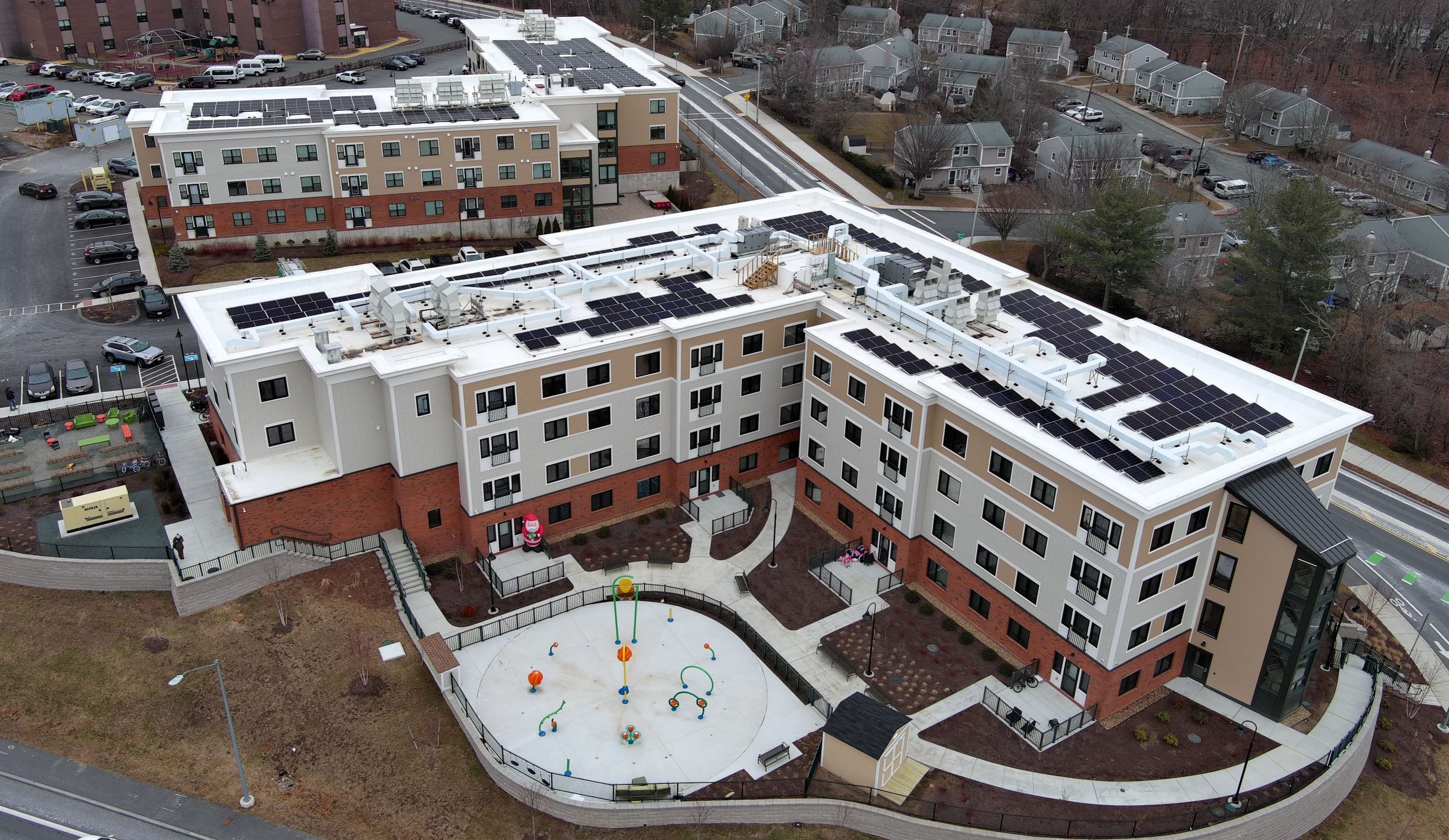 Aerial view of a four-story apartment complex, in two buildings, with a playground in the foreground