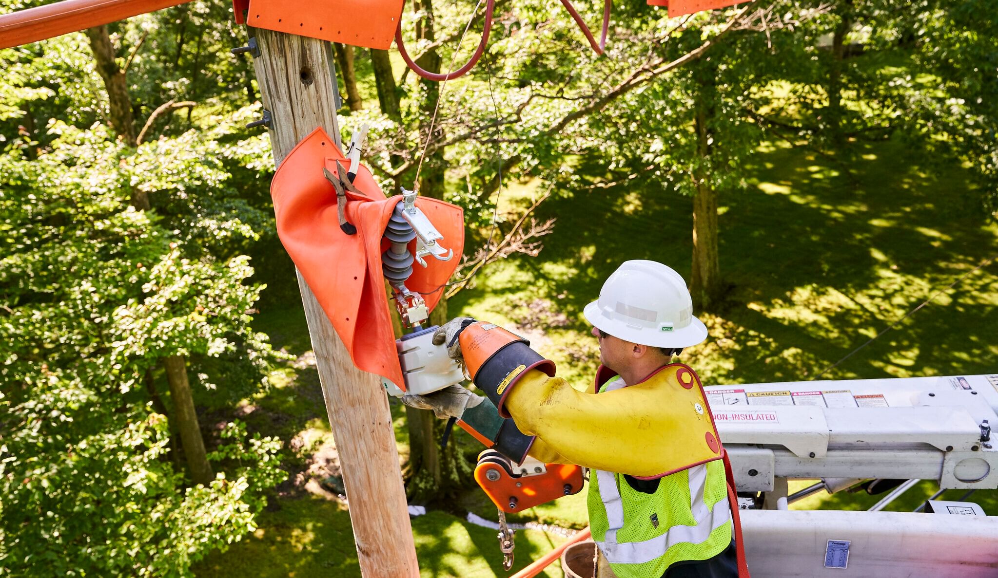 A hard-hatted worker in a cherry-picker doing electrical work
