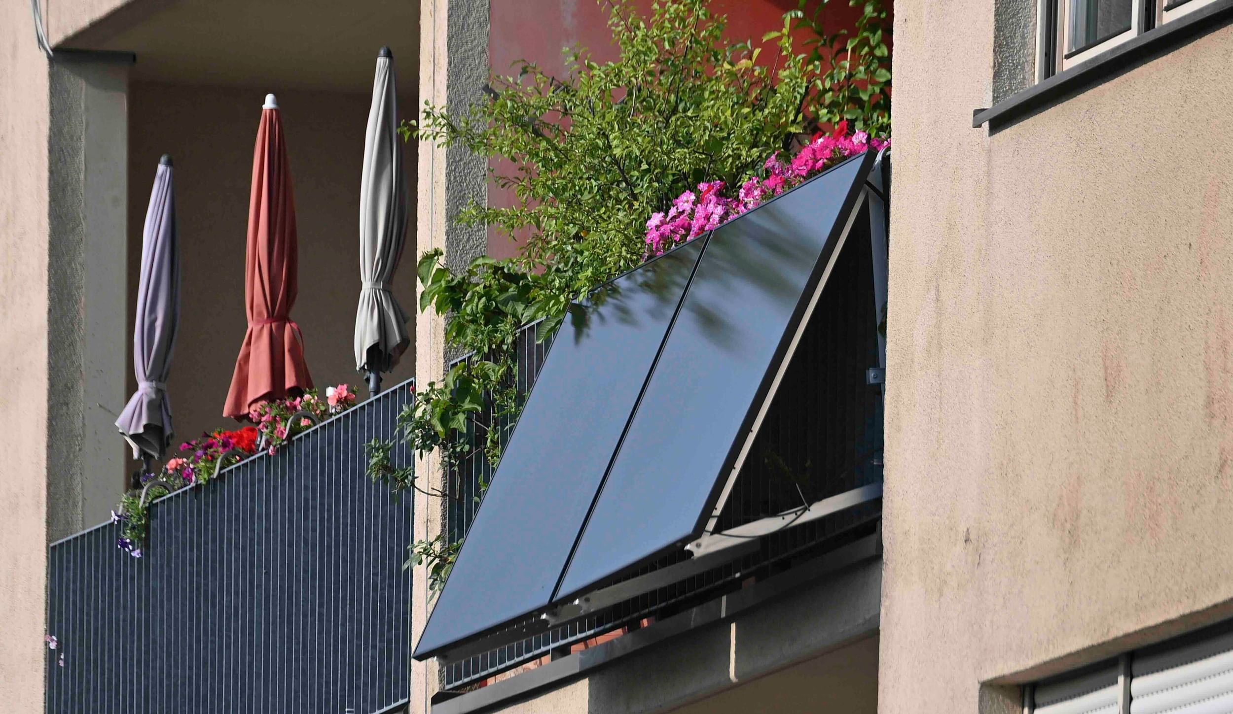 two solar panels hanging from an apartment balcony with flowers