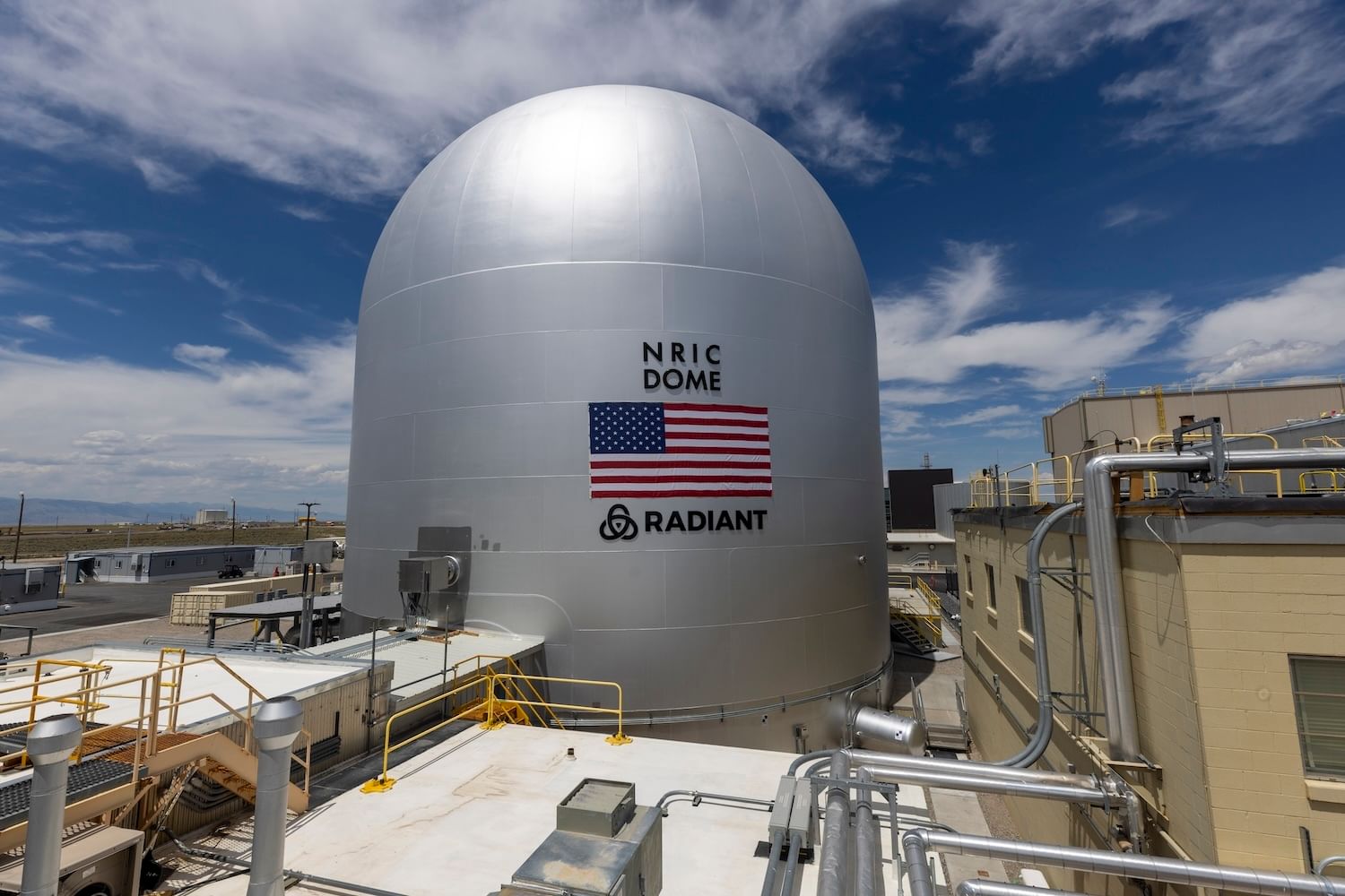 Silver dome with US flag and "NRIC Dome, Radiant" under a blue cloudy sky