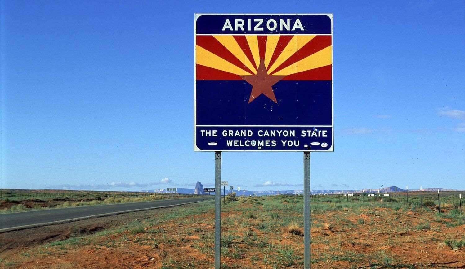 Blue sign with red and yellow stripes and star: Arizona: The Grand Canyon State welcomes you