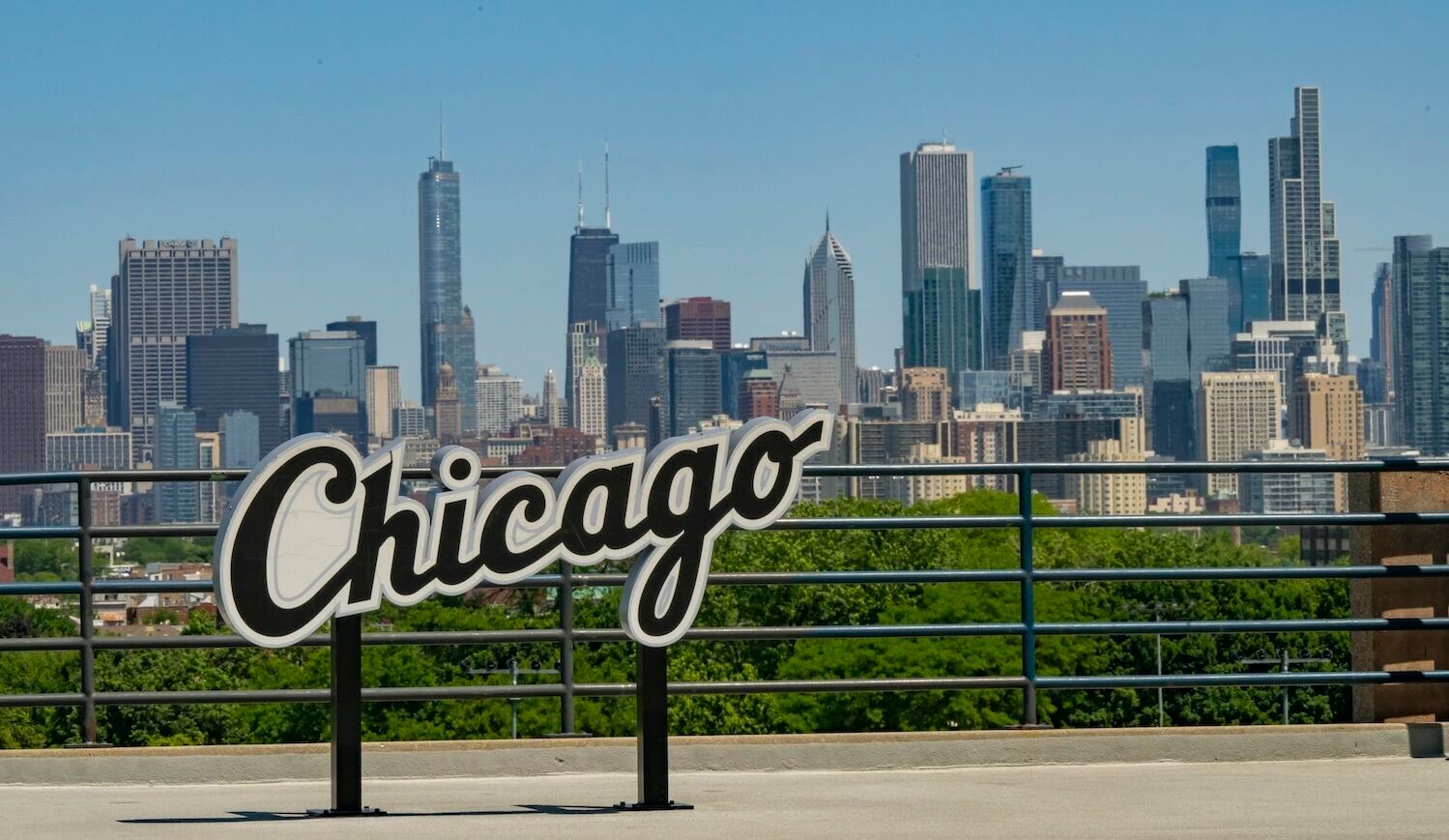 Cursive sign of the word "Chicago" with the city skyline in the distance