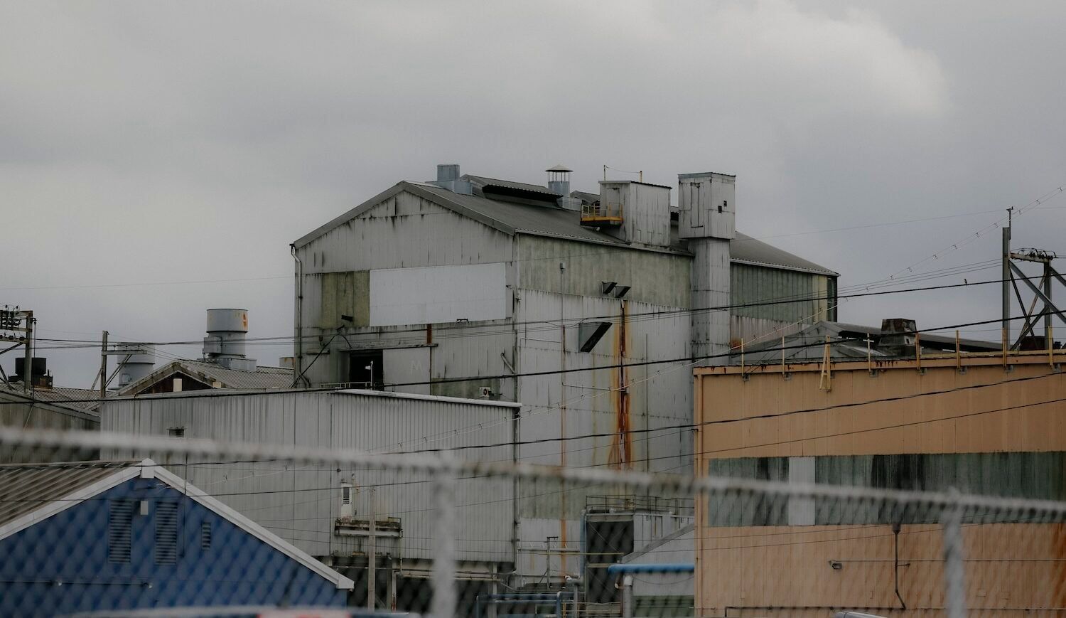 Steel plant seen from a distance behind a chain link fence