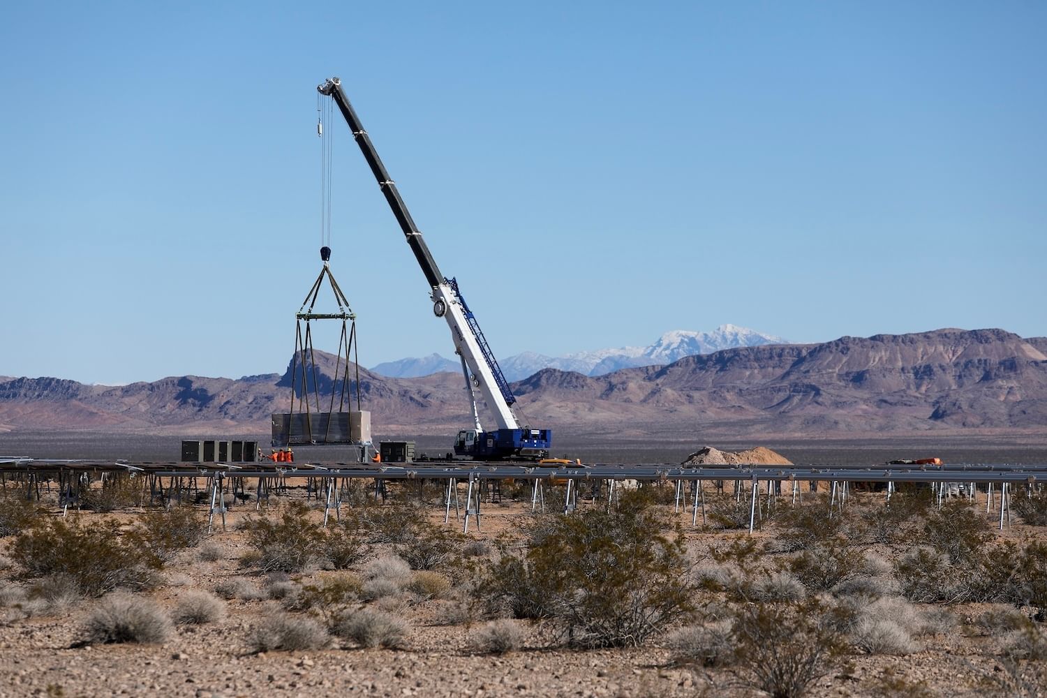 Crane mid-hoist with solar rails amid a desert landscape