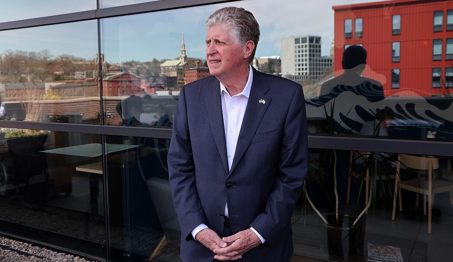 Man in suit outside with reflection of back seen in window