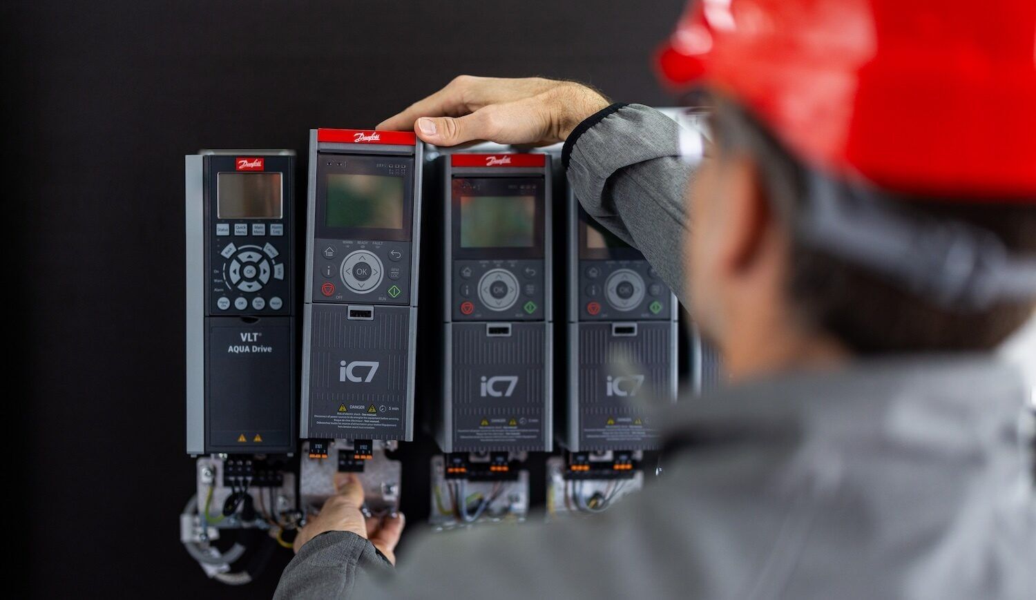 Person in red hard hat, seen from behind, looks at devices