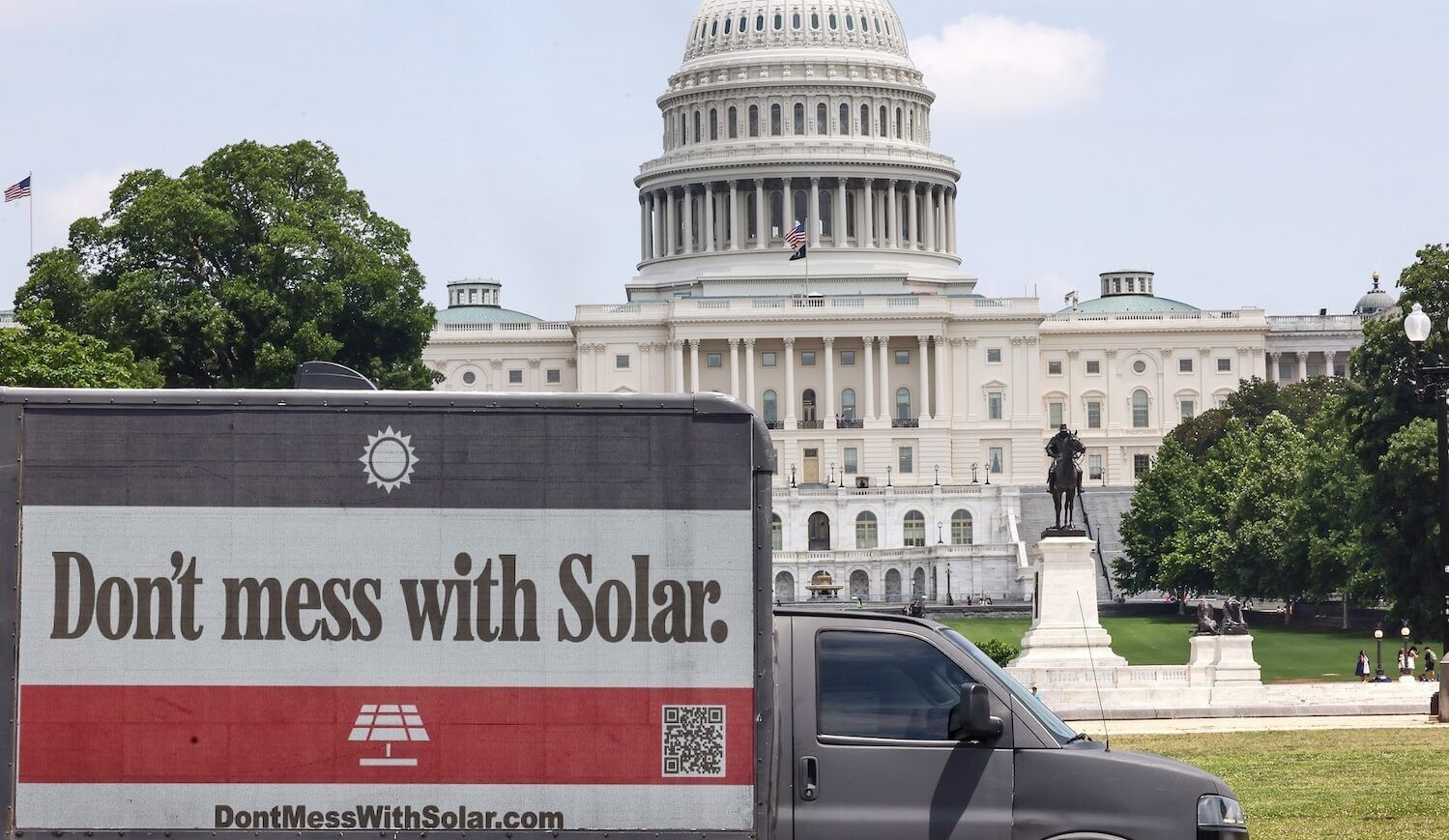 A gray billboard truck with the sign "Don't Mess With Solar" is seen in front of the U.S. Capitol