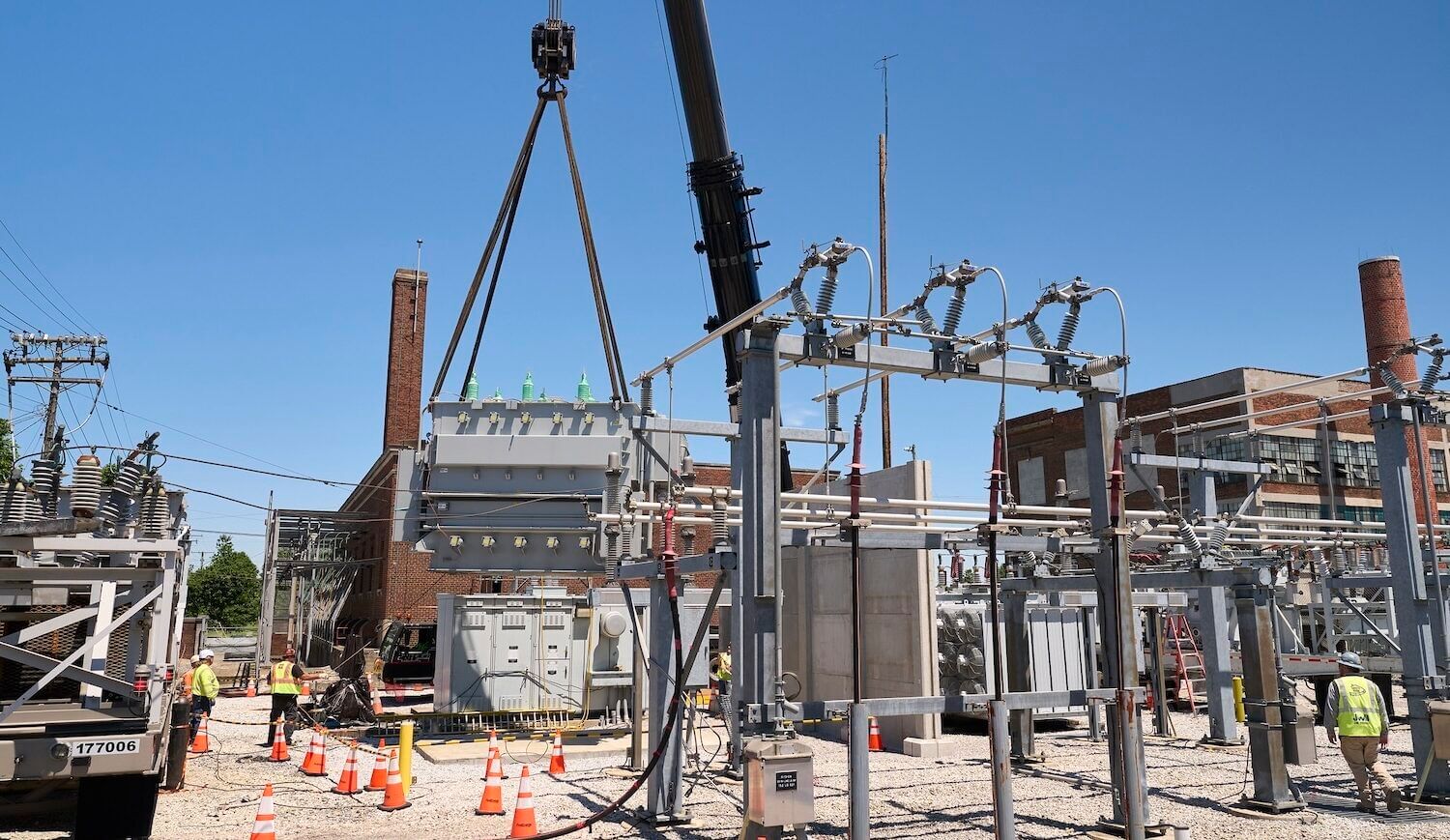 Substation being lowered from a crane at a substation with a truck and some hi-vis-vested workers