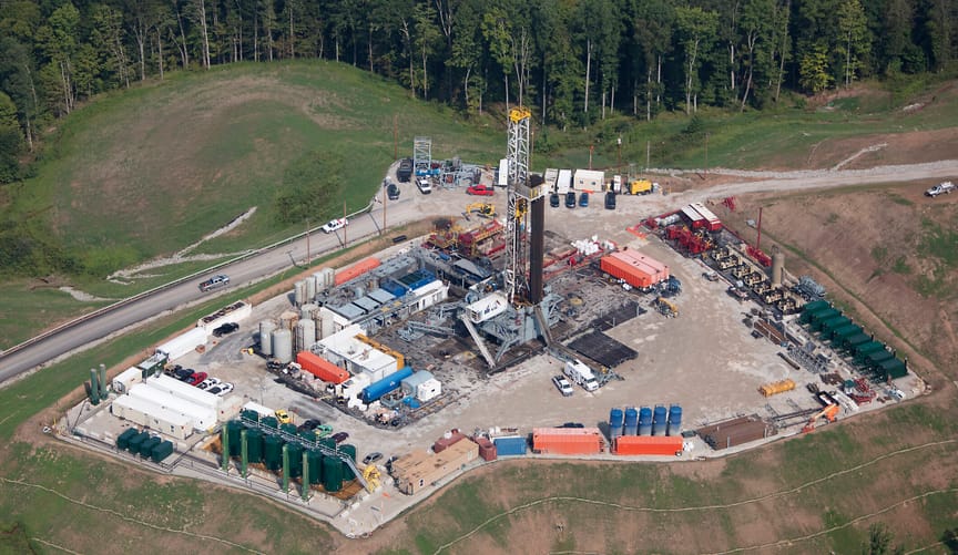 Aerial view of a site with fracking equipment surrounded by forest