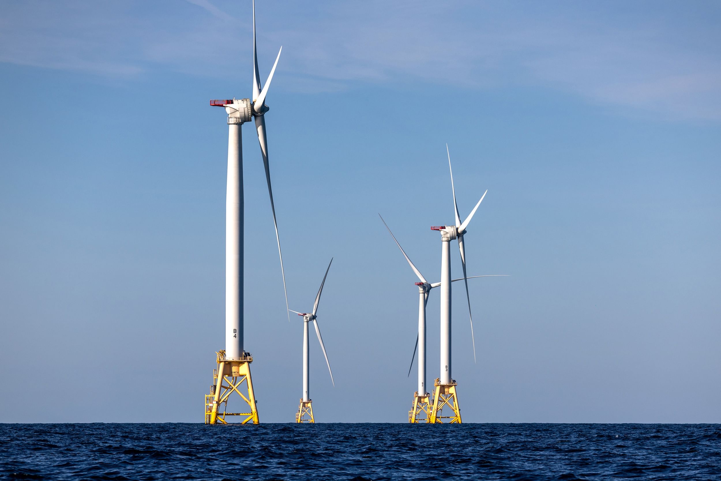 Two wind turbines rise above the ocean.