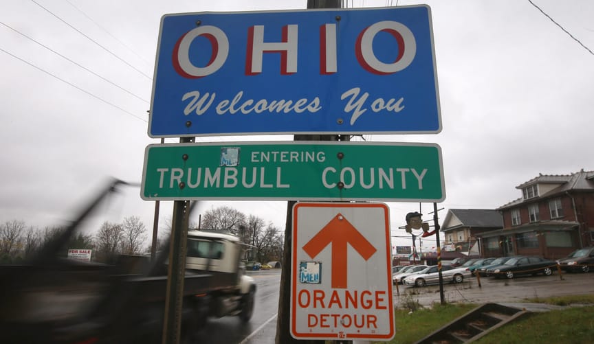 Blue sign on street pole "OHIO Welcomes You": beneath it is green "Entering Trumbull County"