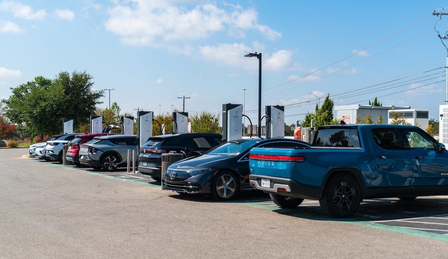 Cars parked in a lot in front of EV charging equipment
