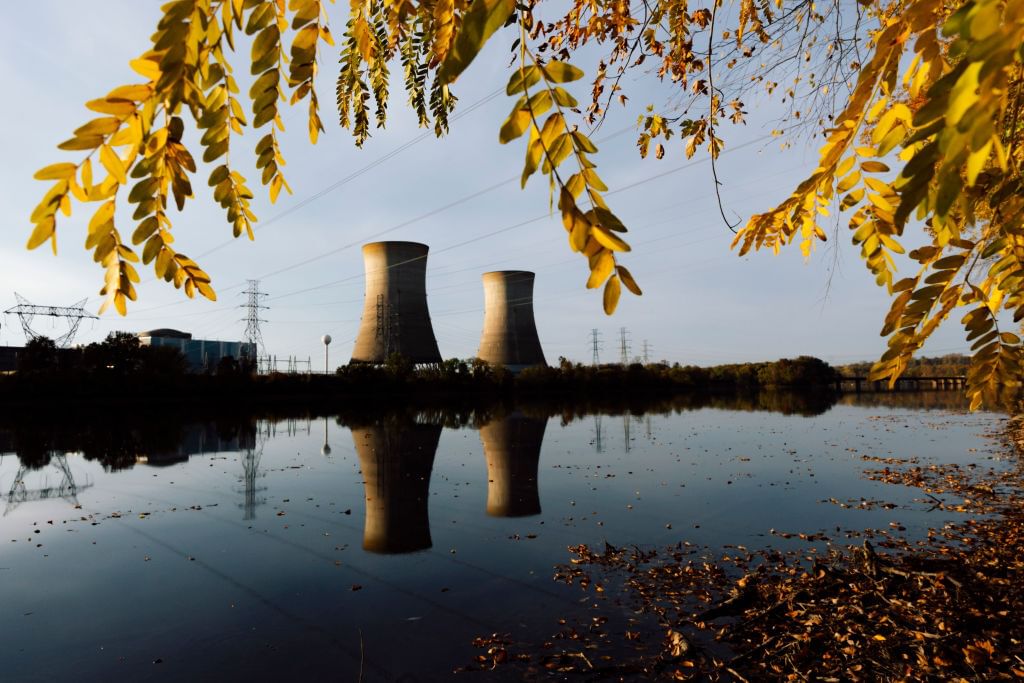 Two nuclear cooling towers are seen reflected in water.