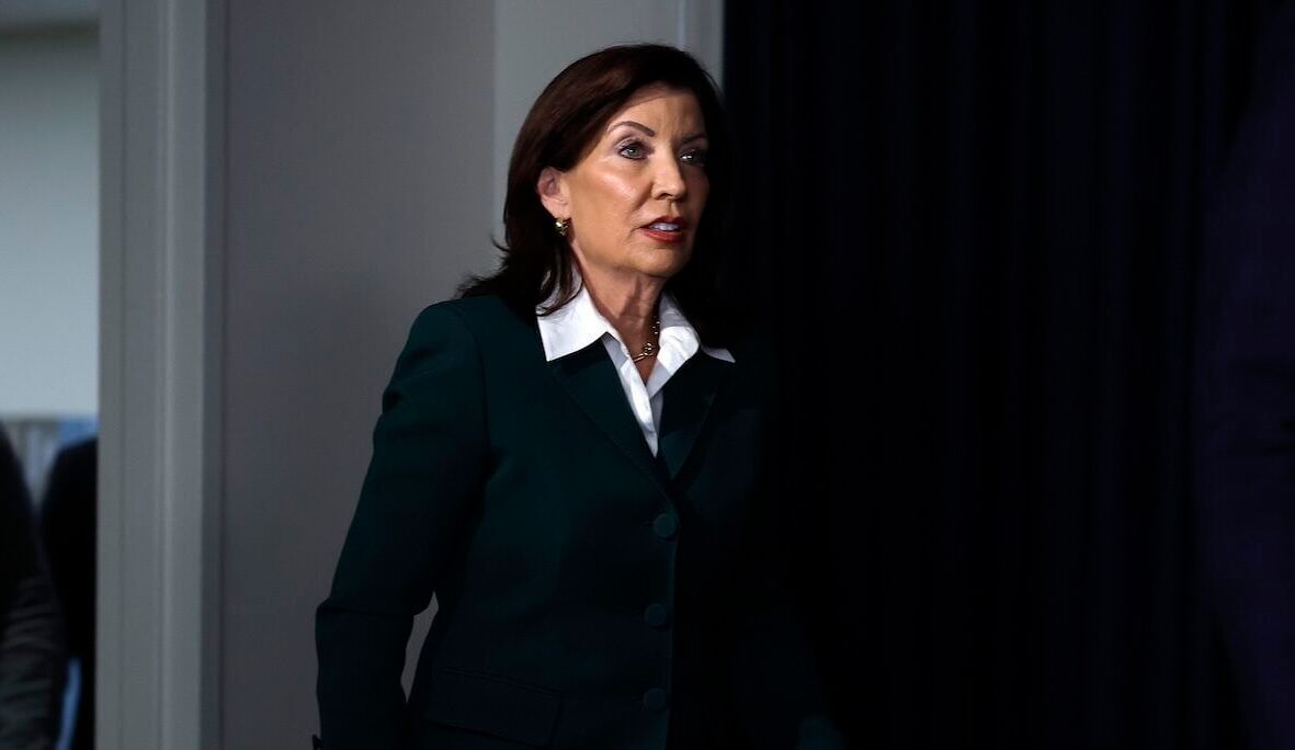 A woman in business attire walks in a dark hall