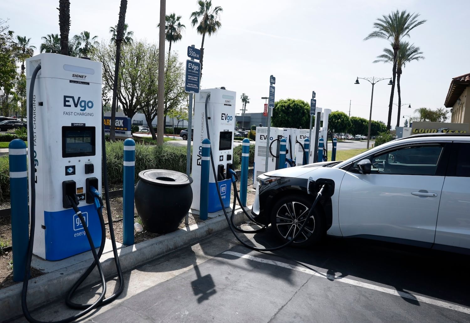 Parking spaces with EVgo chargers and one car charging, palm trees in the distance