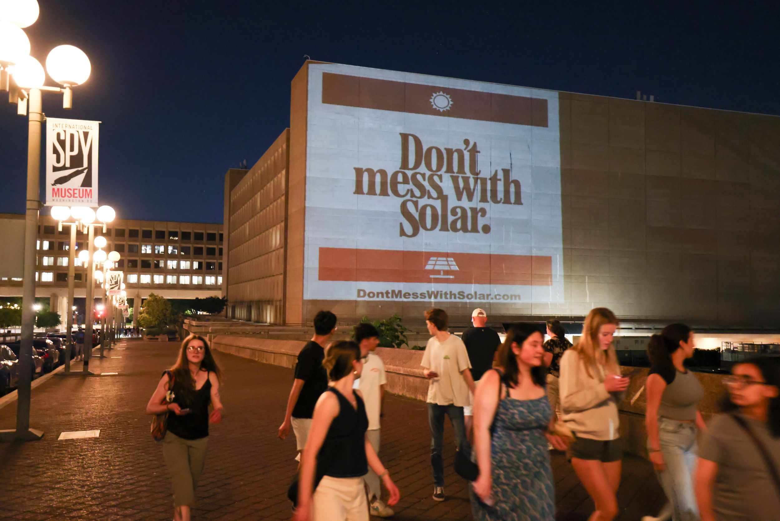 A projection on a building reads Don't mess with solar.