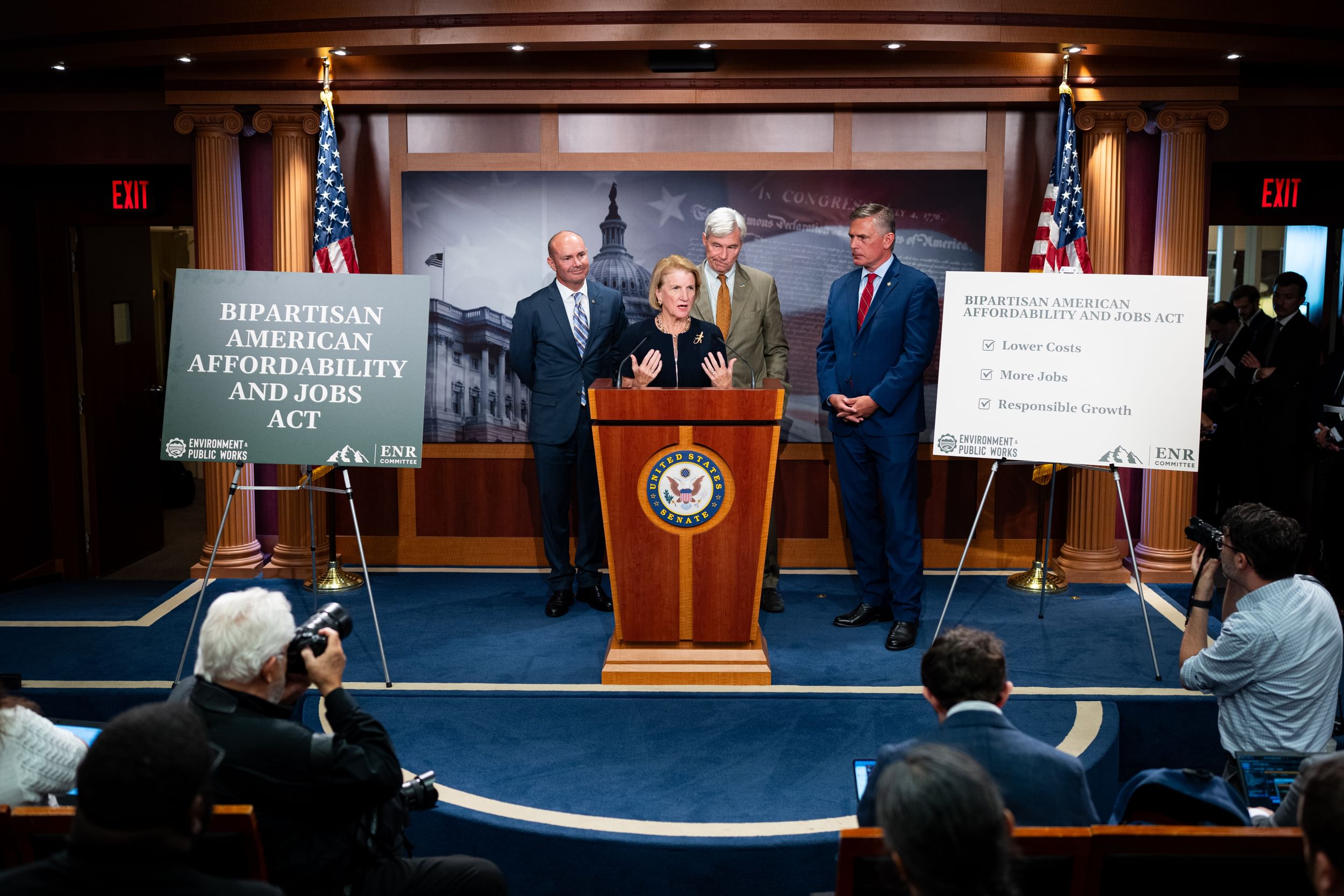 Four senators stand behind a lectern.