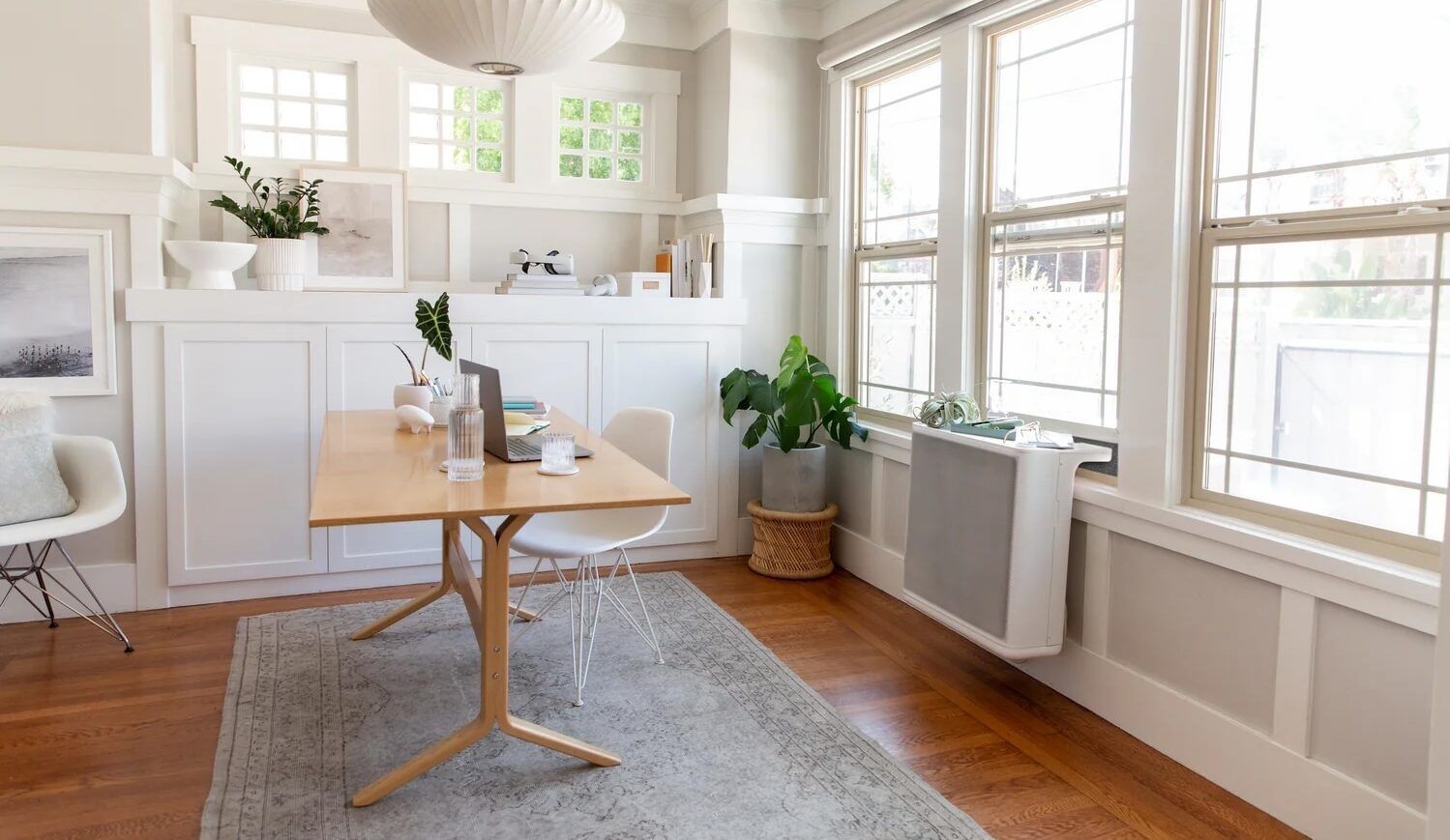 HVAC equipment in a window in a brightly lit room with a desk and two chairs