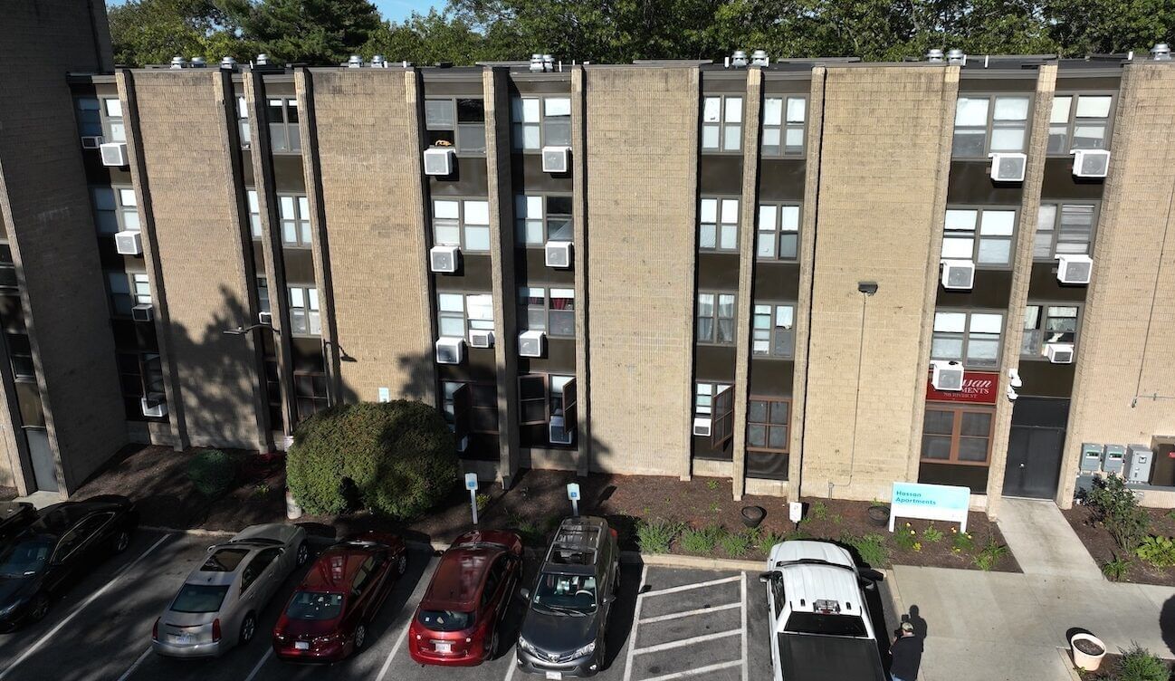 A multifamily building with cars parked in a lot outside