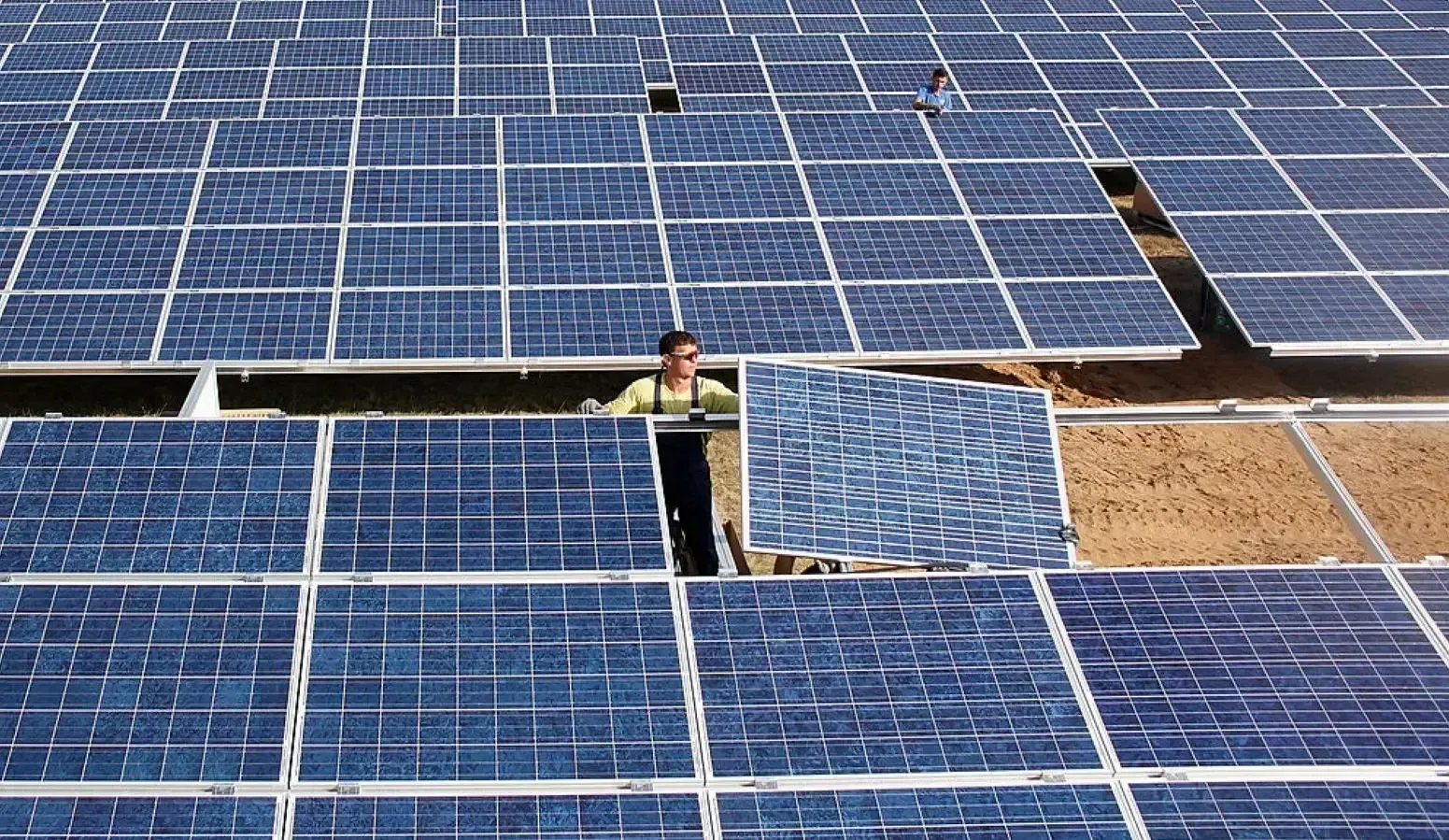 Solar panels shot from above with a man adding a panel to the grid