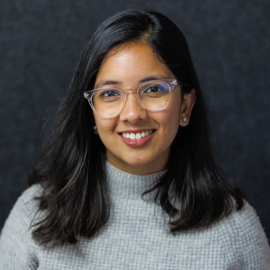Woman with black shoulder-length hair wearing glasses and a gray top