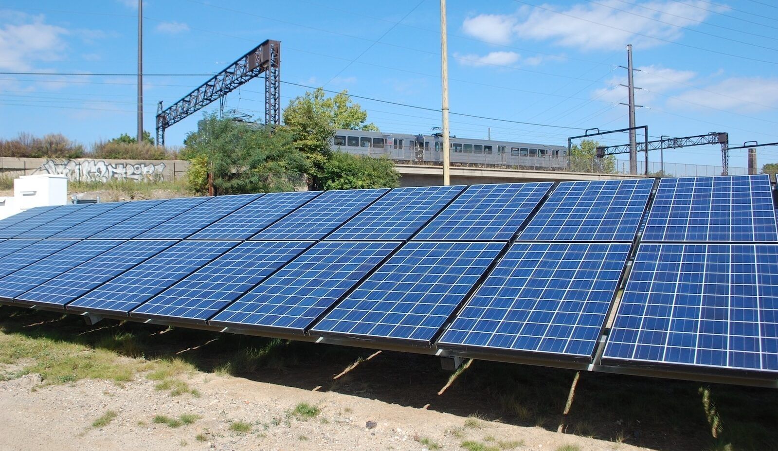 A row of solar panels with a train car passing above