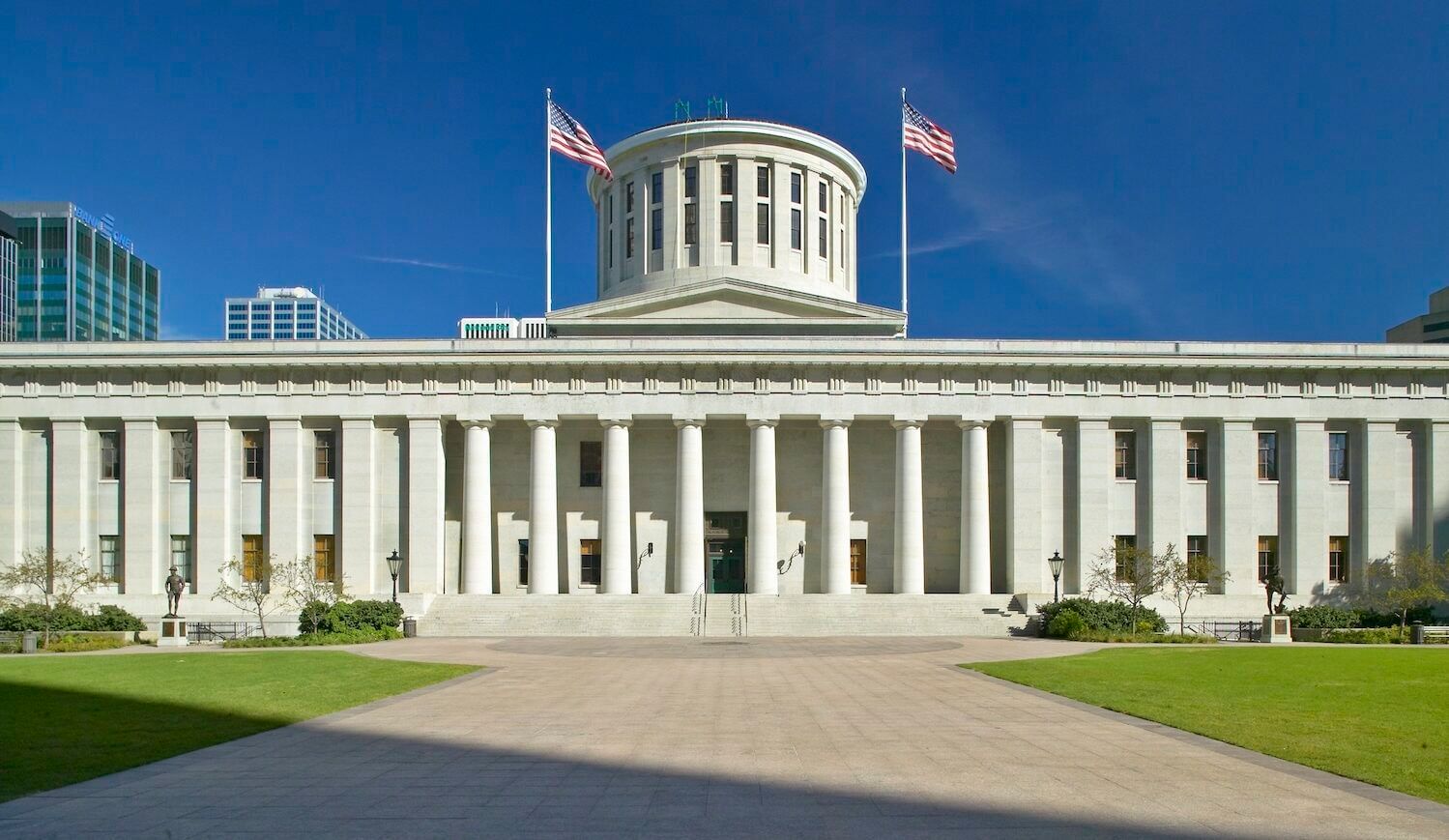 White federal building with two U.S. flags flying on either side of the rotunda