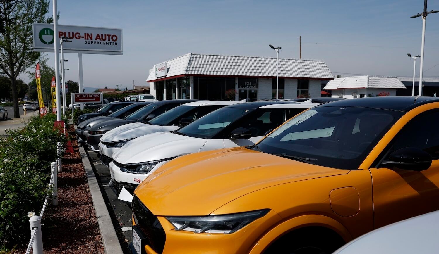 Row of cars in front of a "Plug-in Auto" sign