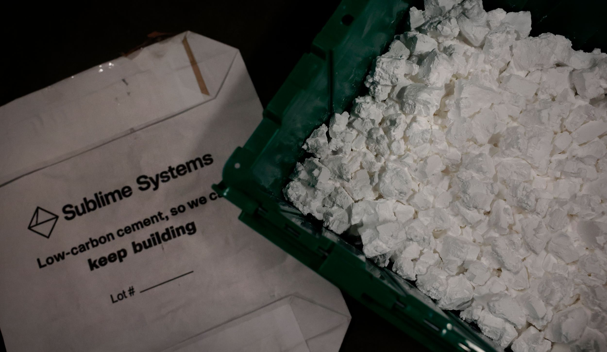 A white packet that says "Sublime Systems: Low-carbon cement, so we can keep building," next to a container of white cement