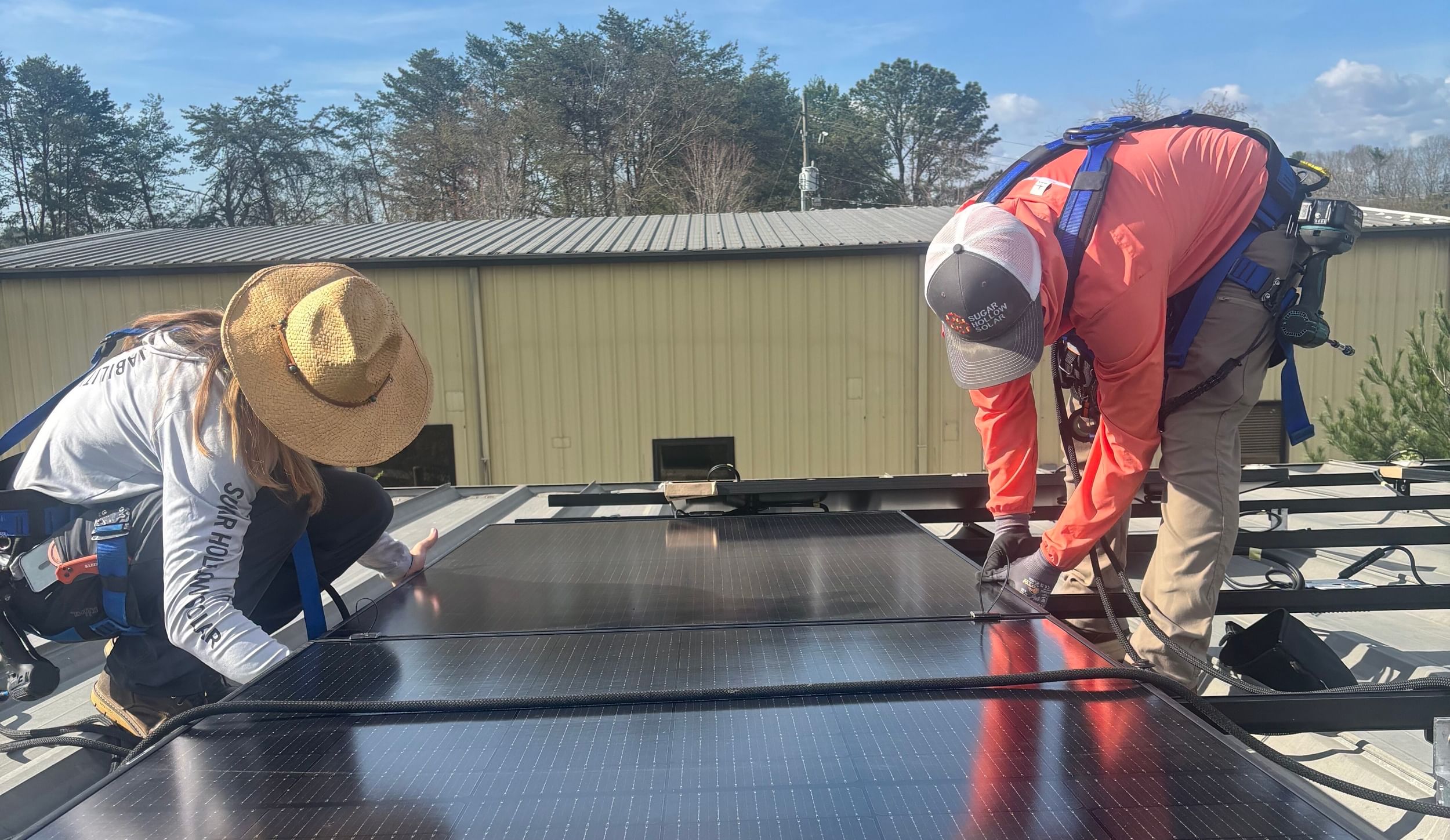 Two people installing panels on a roof