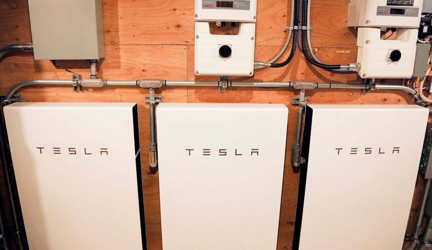 Three Tesla batteries hanging on a wood wall