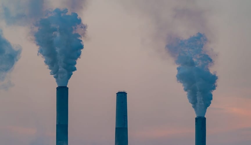 The tops of three stacks at a gas power plant with smoke rising from two of them