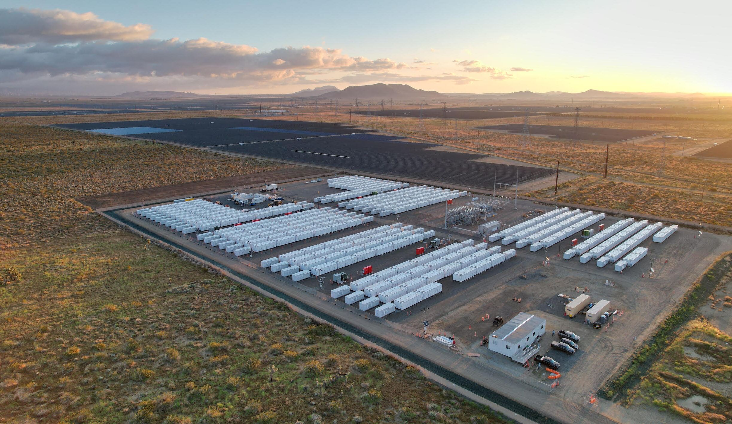 Overhead view of a lot with white battery chargers in row amid a scrubby landscape