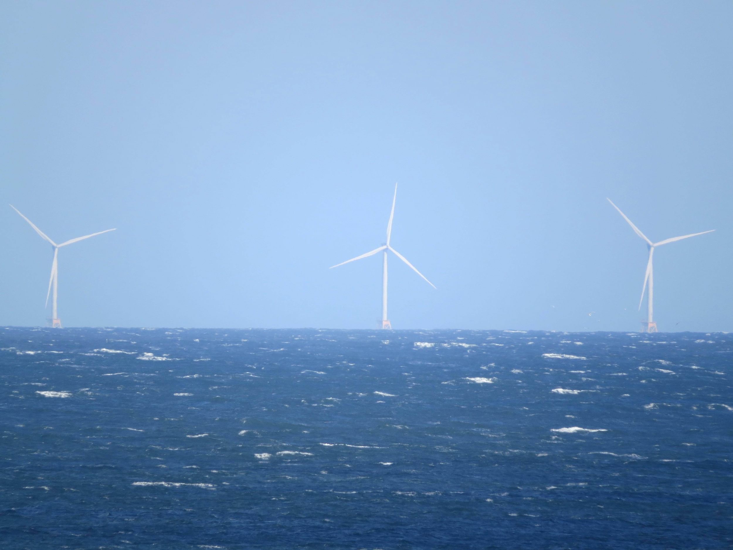 Three offshore wind turbines in the ocean