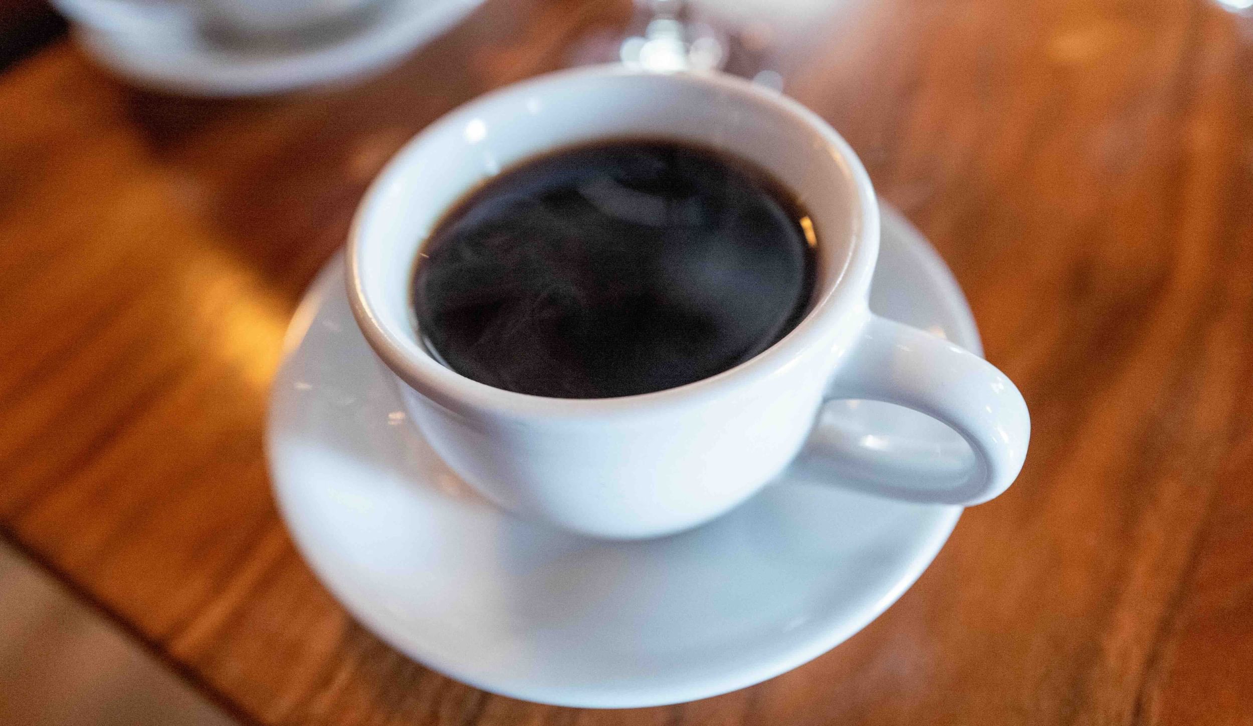 a white mug of steaming coffee on a wooden table