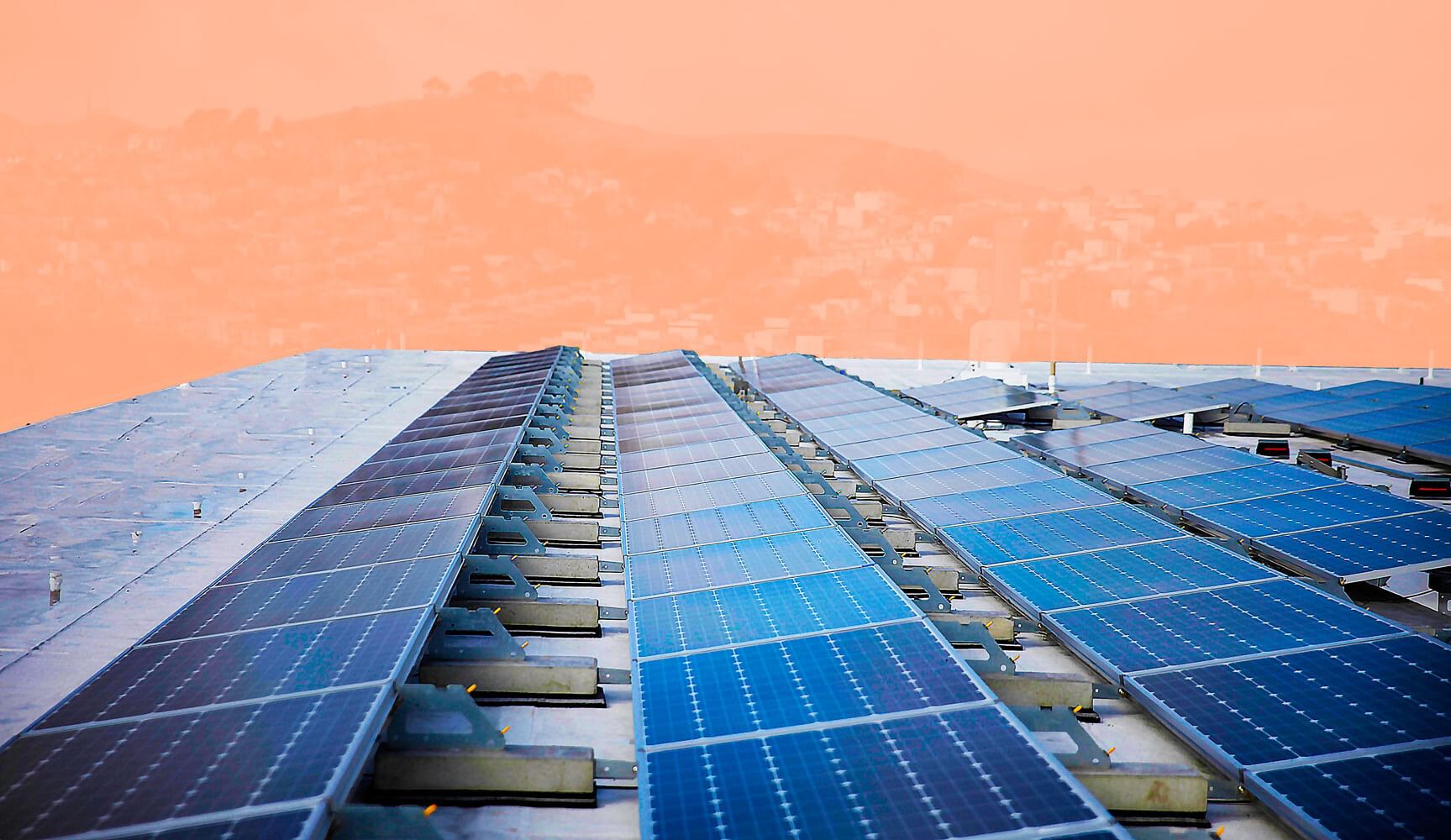 Rows of solar panels on a flat roof, with the hills of San Francisco seen in the background