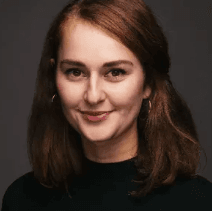 A white woman with shoulder length brown hair and dark eyes wearing a black shirt