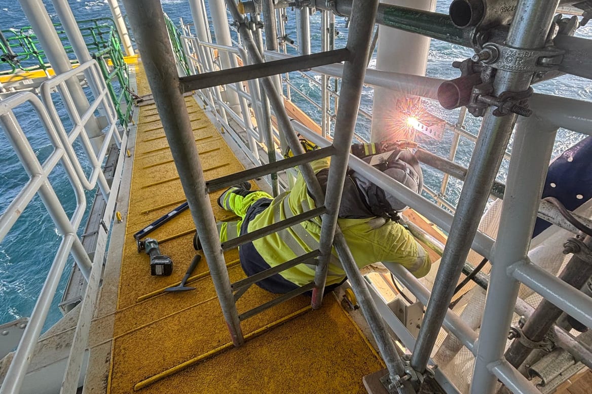 A man laying down works on an offshore wind rig.