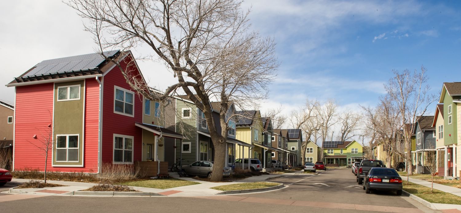 a neighborhood of modest two-story houses with solar panels on their roofs