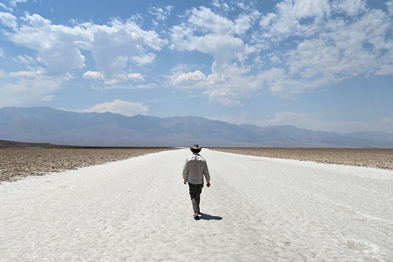 a man in a hat walks in the desert