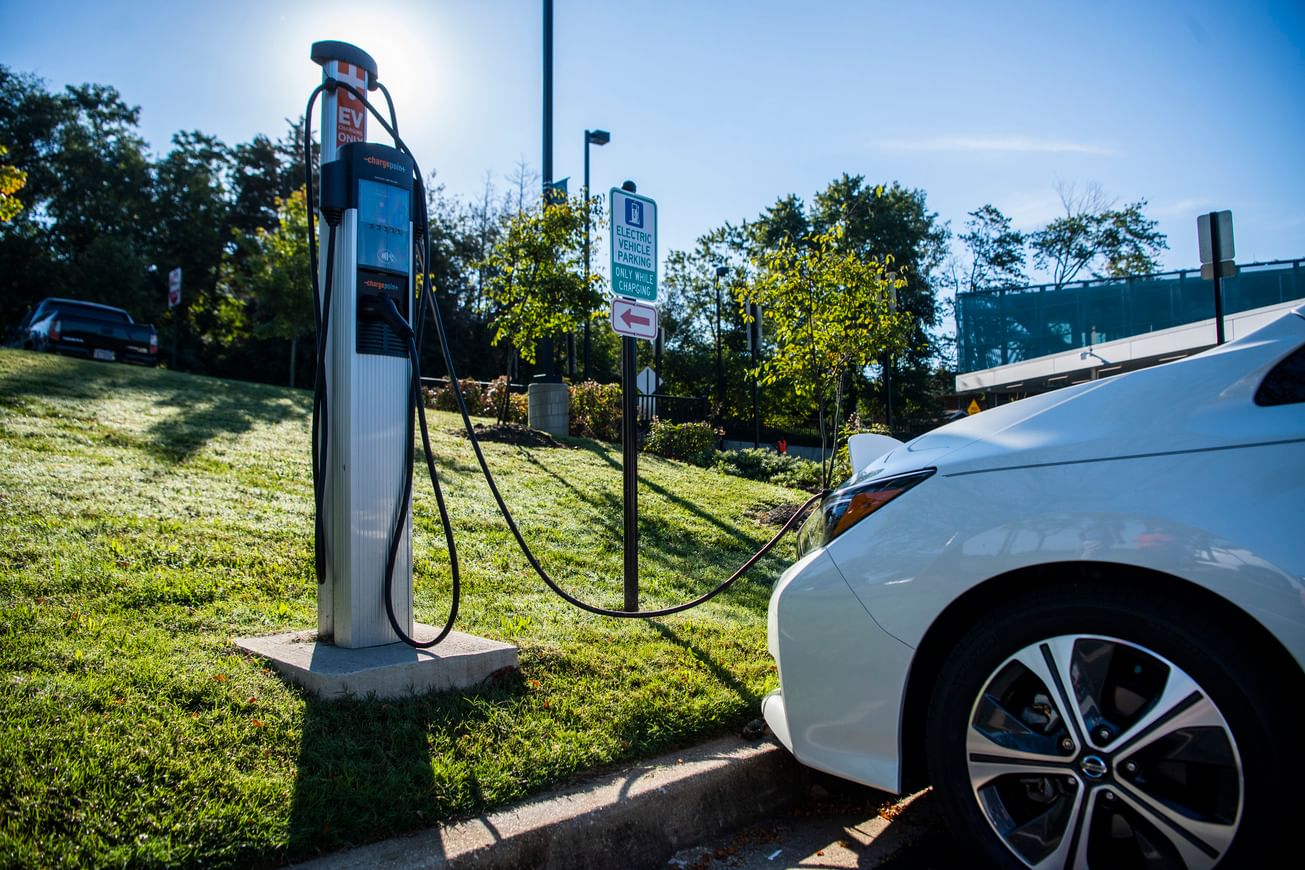 A white electric vehicle is plugged into an EV charger