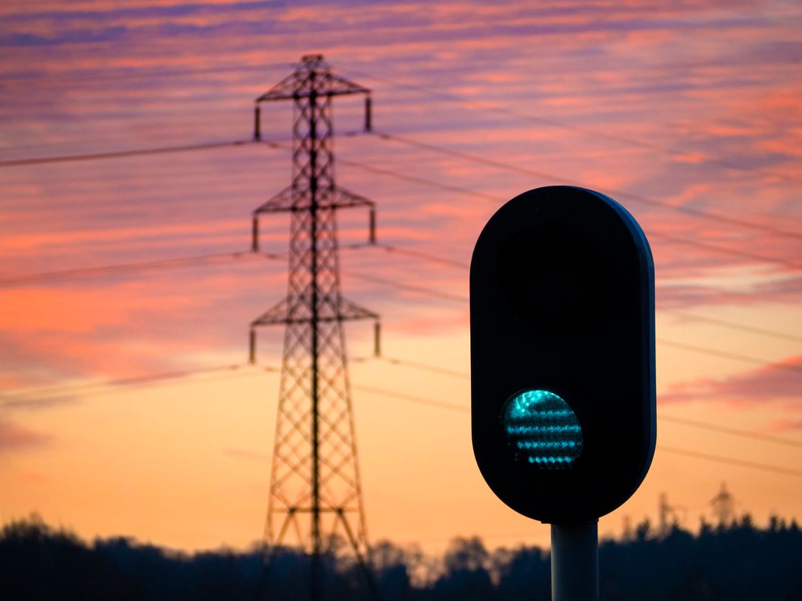 A green traffic signal with transmission lines in the background