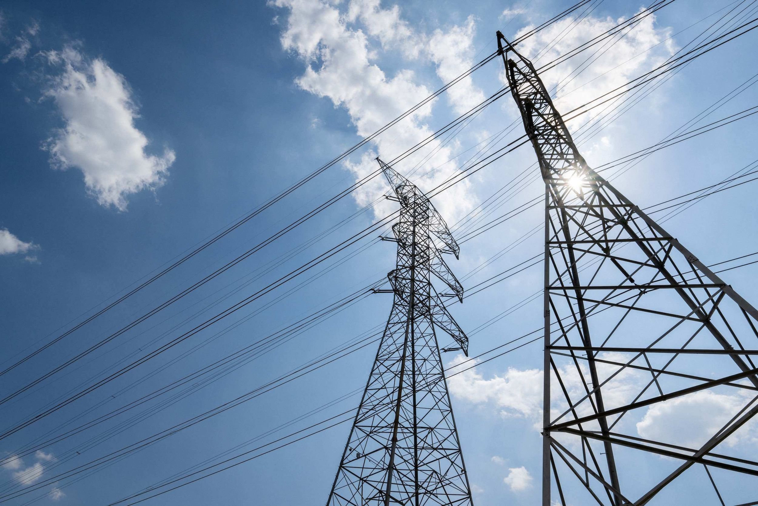 Transmission towers seen from below against a blue sky
